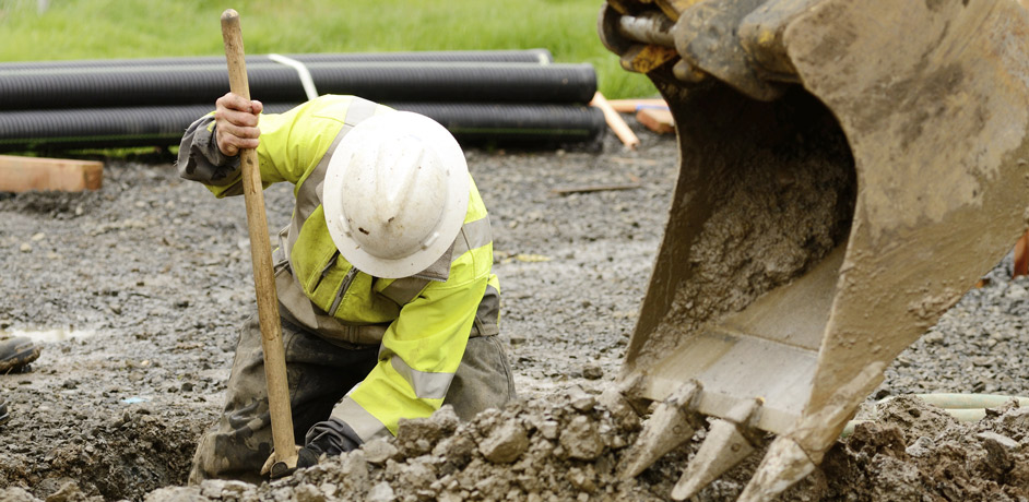 digger and construction worker laying in utilities